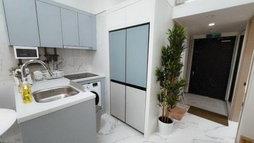 a kitchen with white cabinets and a sink and a plant at Majestic Seoul Stay Central in Seoul