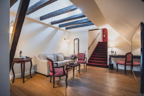 a living room with a couch and chairs and a staircase at Cour du Corbeau Hotel Strasbourg - MGallery Collection in Strasbourg