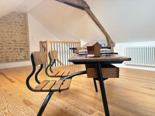 a table and a chair in a room with a table at La clairiere Maison spacieuse rénovée joliment décorée tout confort 12 p 2 sdb 2 wc grand jardin clos, belle terrasse aménagée, parking privatif, ping pong baby foot proche Omaha Beach et Bayeux in Crouay