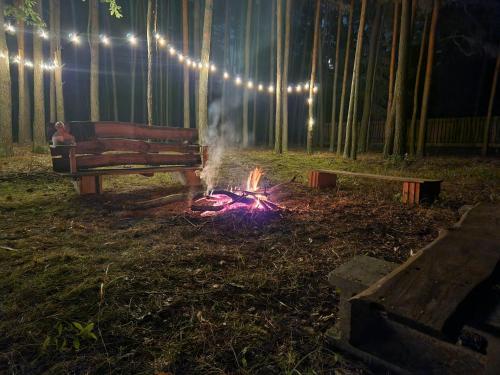 a person sitting next to a fire next to a bench at Leśna Osada Wieliszew in Wieliszew