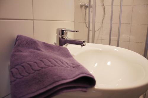 ein lila Handtuch auf einem Waschbecken in der Unterkunft Lindencafe Luckenwalde in Luckenwalde