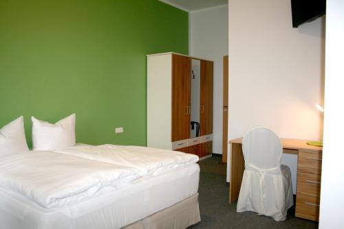 a bedroom with a bed and a desk and a chair at Lindencafe Luckenwalde in Luckenwalde