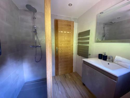 une salle de bain avec un lavabo et une douche avec un miroir dans l'établissement Mountain Cabin - vue montagne - 4 personnes, aux Houches
