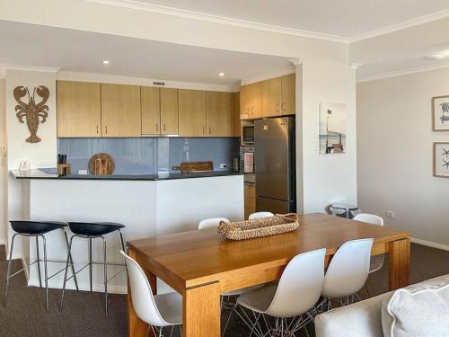 a kitchen with a wooden table and white chairs at Unit 32 - Avoca Palms Resort in Avoca Beach