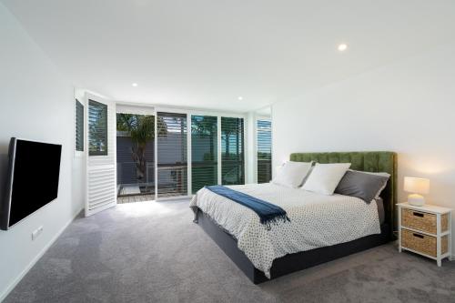 a bedroom with a bed and a flat screen tv at Beachside Retreat with Private Pool in Papamoa