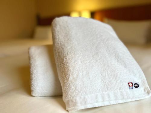 two towels sitting on top of a bed at Hotel Monterey Sendai in Sendai