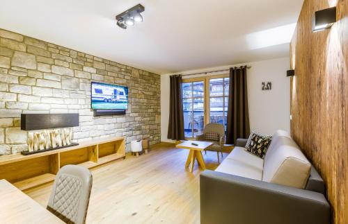 salon z kanapą i kamienną ścianą w obiekcie Bolodges Apartments by Alpin Rentals w Saalbach Hinterglemm