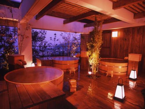 a room with two tubs and a table and lights at Kannawa Onsen Hotel Sansuikan in Beppu