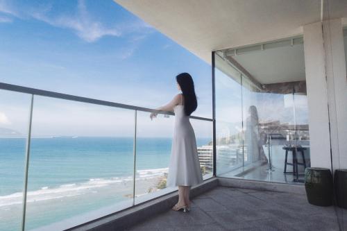 a woman in a white dress standing on a balcony overlooking the ocean at The Shanhaitian Resort Sanya, Autograph Collection in Sanya