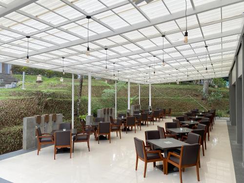 a restaurant with tables and chairs under a roof at Lembang Asri Resort in Lembang