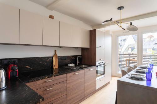 une cuisine avec des armoires blanches et un comptoir noir dans l'établissement L'Orée Des Lices - Appt de standing à Rennes, à Rennes