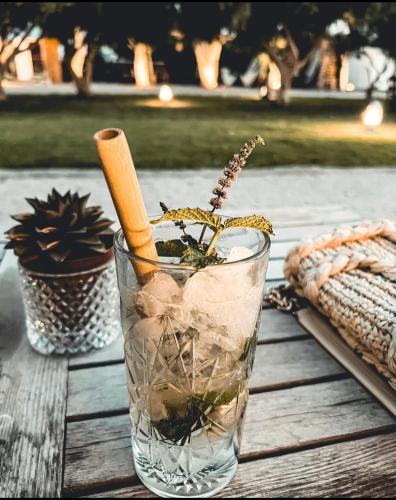 a glass vase sitting on a wooden table with a drink at Eco Beach And Magic Garden Hotel in Gennadi