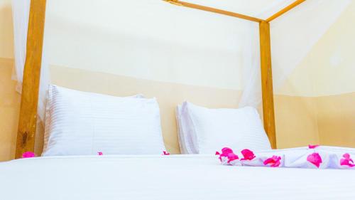 two white beds with pink flowers on top of them at Sands Inn Hotel in Pwani Mchangani