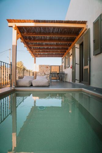 a swimming pool with a pergola and a house at Villa Rosa - Luxury Villas with Panoramic Views in Lagoúdi Zía