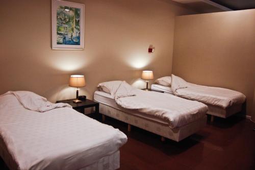 a room with three beds and two tables with lamps at Ambassador Suites Antwerp in Antwerp
