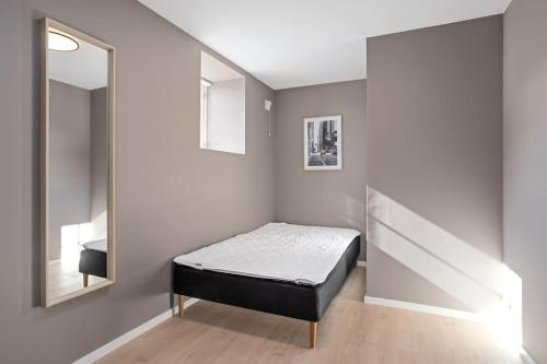 a small bedroom with a bed and a mirror at 6 sov l Perfekt for StayCATION in Drammen
