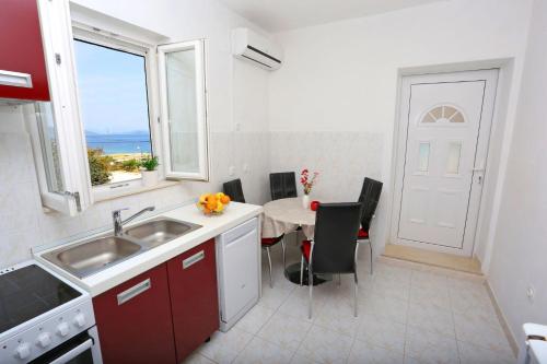eine Küche mit Spüle und Tisch mit Stühlen in der Unterkunft Apartment Marija in Drvenik Mali