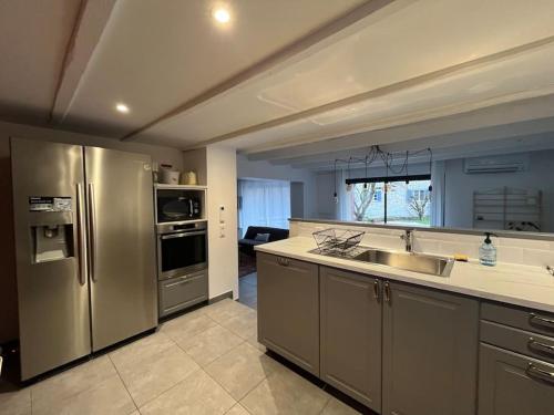 une cuisine avec un réfrigérateur en acier inoxydable et un évier dans l'établissement Le gite dErin, à Saint-Yrieix-sous-Aixe