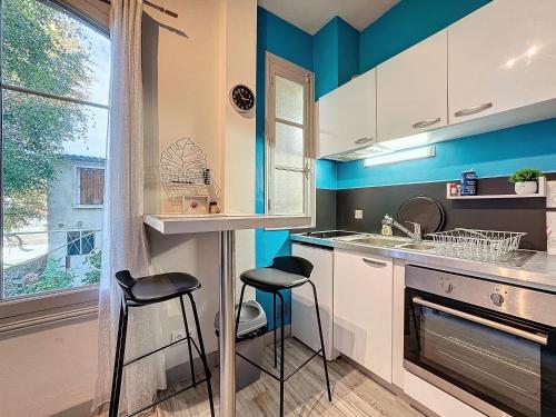 a kitchen with two stools in a kitchen with blue walls at Studio Av thermale Cham (C) in Chamalières
