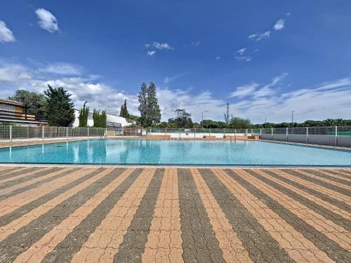 une grande piscine entourée d'une clôture. dans l'établissement T1 très fonctionnel résidence Tennis Village piscine, Ping Pong, citypark, boulodrome, au Cap d'Agde