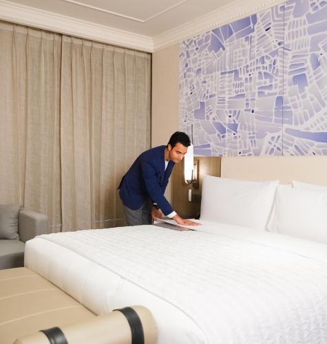 a man standing next to a bed in a hotel room at Le Meridien Amritsar in Amritsar
