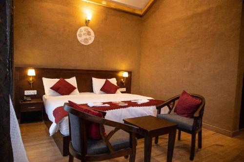 a bedroom with a bed and a table and chairs at Maatidera Resort Kanatal The Boutique stay in the Lap of Himalayas in Kanatal