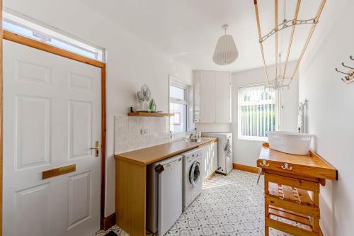a kitchen with a washing machine and a white door at Anthony House in Kippford