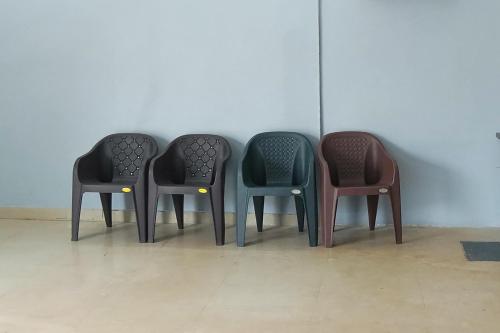 four chairs lined up in a row against a wall at Hotel O Shining Star in Bhilai