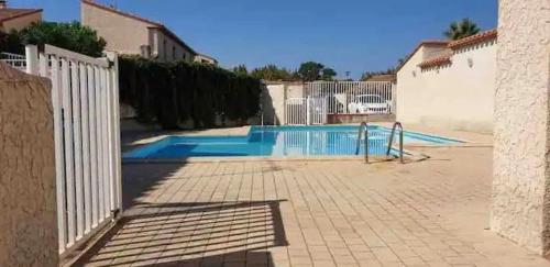 une piscine avec une clôture blanche à côté d'un bâtiment dans l'établissement Face Lagune superbe appartement de plain pied avec parking - 6BAIE12, à Saint Cyprien Plage