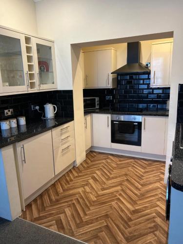 a kitchen with white cabinets and a wooden floor at Beautifully presented Victorian Apartment within walking distance to Llandudno beach in Llandudno