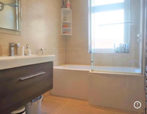 ein Badezimmer mit Badewanne, Waschbecken und Dusche in der Unterkunft Family friendly house in Purley