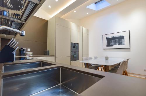 a kitchen with a stainless steel counter and a table at Soho Mews House in London