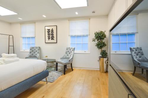 a bedroom with two chairs and a bed and windows at Soho Mews House in London