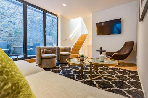 a living room with a couch and chairs and a tv at Soho Mews House in London
