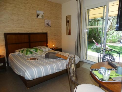 une chambre avec un lit, une table et une fenêtre dans l'établissement Gîtes en B&B Le Clos de la Cerise, à Châteauneuf-du-Pape