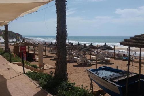 a beach with umbrellas and chairs and the ocean at Apprt cosy près plage des Nations in Sale