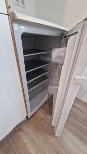 an empty refrigerator with its door open in a kitchen at Voll ausgestattet, Nähe Heiltherme Bad Waltersdorf in Ebersdorf