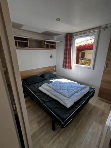 un lit dans une petite pièce avec une fenêtre dans l'établissement MOBILHOME 2 Chambres 268 VILLAGE SIBLU, à Gastes