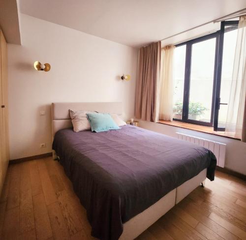- une chambre avec un grand lit dans une pièce dotée de fenêtres dans l'établissement Homeloveparis, à Paris