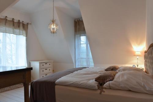 ein Schlafzimmer mit einem Bett, einer Kommode und einem Kronleuchter in der Unterkunft Ziegeleivilla in Glücksburg