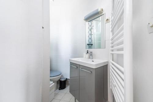 une salle de bain blanche avec un lavabo et des toilettes dans l'établissement Studio confortable au centre Paris 14ème, à Paris