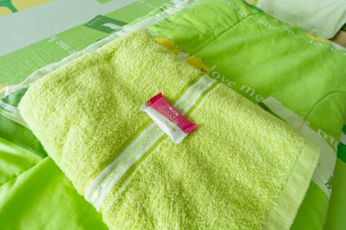 a green blanket with a bottle on top of it at Tat Hotel in Bangkok