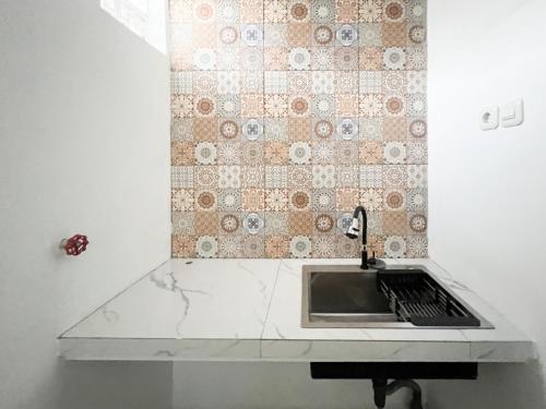a kitchen counter with a sink and a tiled wall at Urbanview Hotel Dommy Yogyakarta by RedDoorz in Ngabean