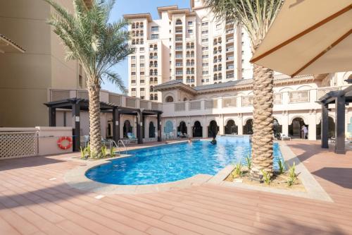 a swimming pool in the middle of a building with palm trees at Free housekeeping visits during your stay - StayShort - Stylish 1-Bedroom Retreat with Pool in Vibrant Jumeirah Golf Estates in Dubai