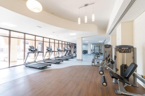 a gym with a row of treadms and cardio machines at Free housekeeping visits during your stay - StayShort - Stylish 1-Bedroom Retreat with Pool in Vibrant Jumeirah Golf Estates in Dubai