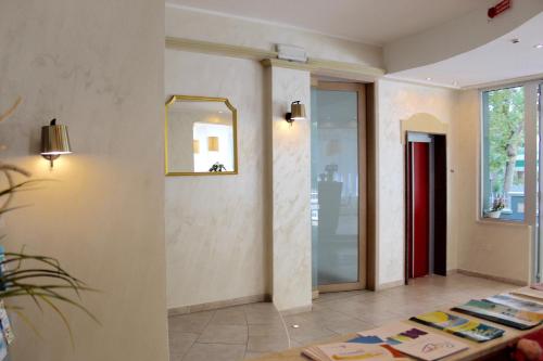 a lobby with a mirror and a table with books at King Hotel in Cesenatico