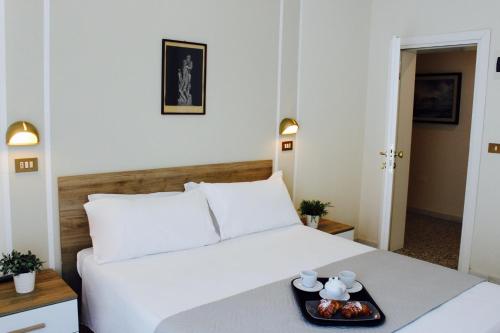 a white bed with a tray of food on it at King Hotel in Cesenatico