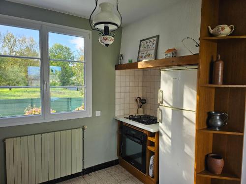 une cuisine avec un réfrigérateur blanc et une fenêtre dans l'établissement La maison d’Henri, à Sailly-Flibeaucourt