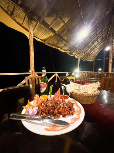 a plate of food on a table with a bottle of beer at Red Crab Eco Resorts in Cabo de Rama