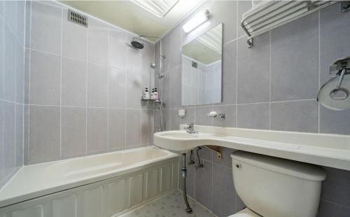 a bathroom with a sink and a toilet and a mirror at Empire Motel in Cheonan